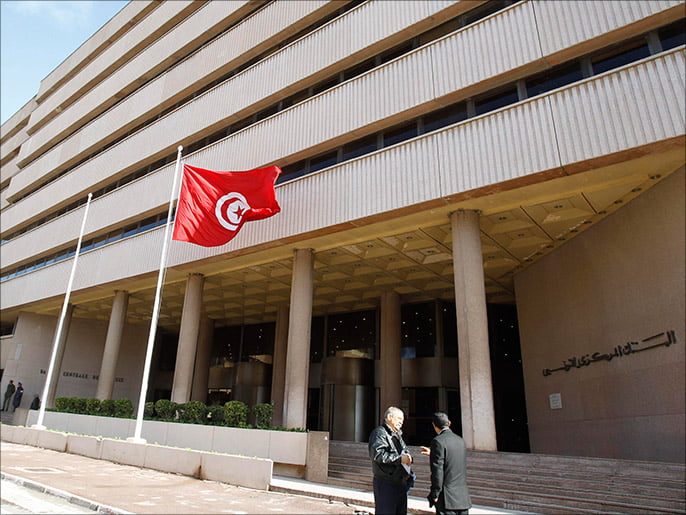 Des hommes parlent devant la Banque centrale à Tunis, le 27 décembre 2013. La banque centrale tunisienne a relevé jeudi son taux d'intérêt de référence de 4 pour cent à 4.5 pour cent, citant les pressions inflationnistes, tout en réduisant son taux de réserves obligatoires pour assurer une liquidité adéquate dans le l’économie, a-t-il déclaré jeudi. REUTERS/Zoubeir Souissi (TUNISIE - Tags: AFFAIRES)